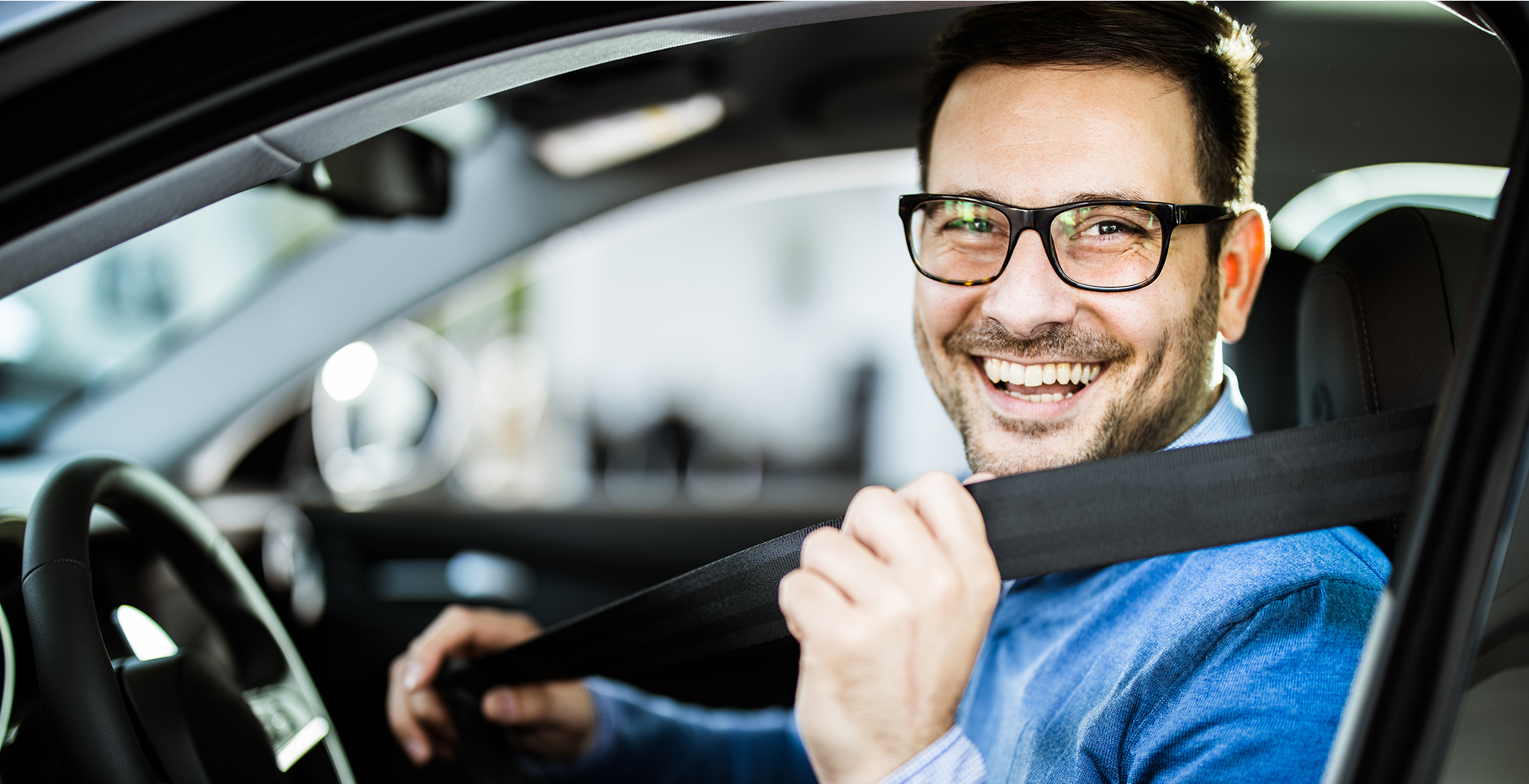 Man smiles while he practices seat belt safety